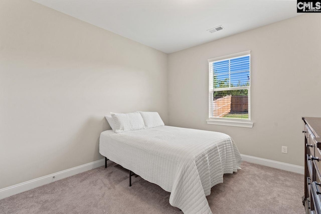 bedroom with baseboards, visible vents, and light colored carpet