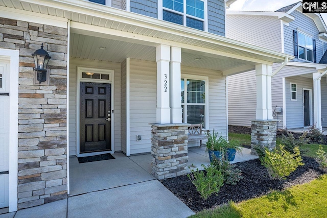 property entrance with a porch and stone siding