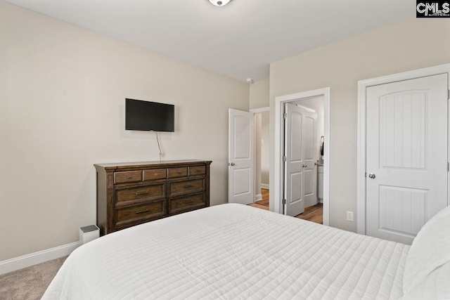 carpeted bedroom featuring baseboards and ensuite bathroom