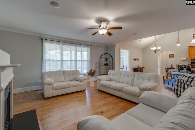 living room with a fireplace, baseboards, light wood-type flooring, and ceiling fan with notable chandelier