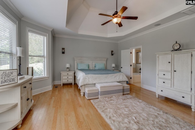 bedroom featuring a tray ceiling, light wood-style flooring, crown molding, and baseboards