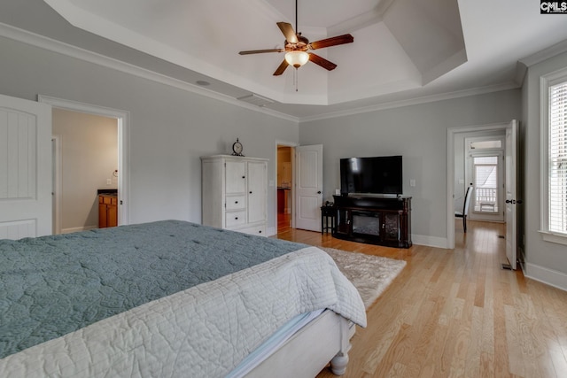 bedroom with a ceiling fan, crown molding, light wood-style floors, and a raised ceiling