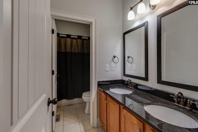 bathroom featuring toilet, tile patterned floors, a sink, and double vanity