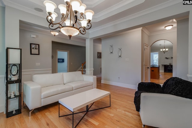 living area with light wood finished floors, stairway, crown molding, and an inviting chandelier