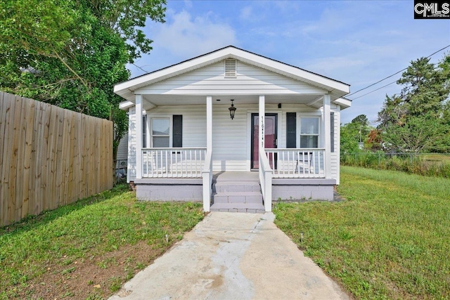 bungalow-style home featuring covered porch, fence, and a front yard