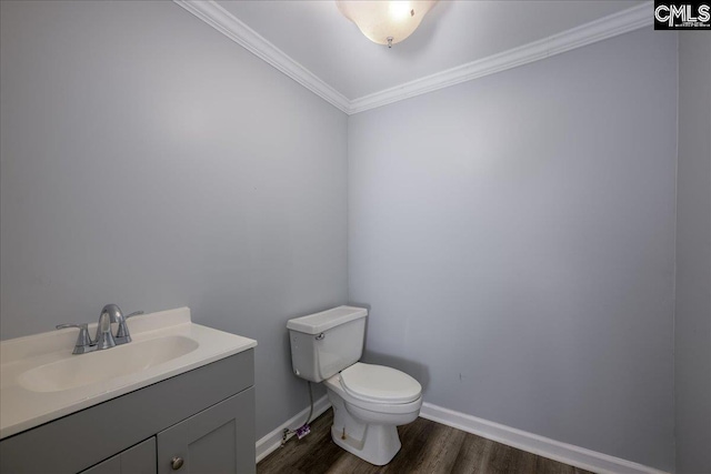 half bathroom with wood finished floors, ornamental molding, toilet, vanity, and baseboards