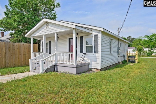 view of front of home with fence, covered porch, and a front yard