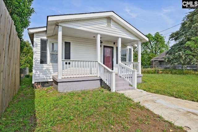 view of front of home featuring fence, a porch, and a front yard