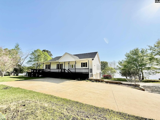 farmhouse featuring driveway, a front yard, and covered porch