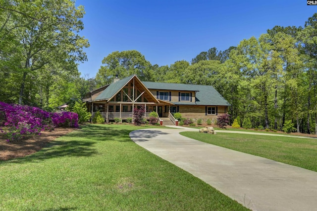 log cabin featuring stone siding, a porch, a front lawn, and concrete driveway