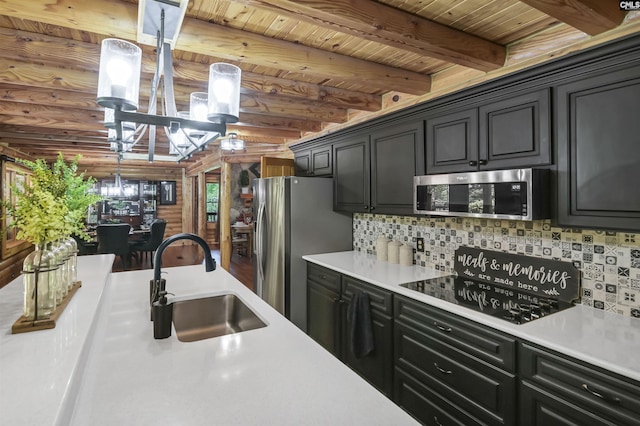 kitchen featuring stainless steel appliances, a sink, an inviting chandelier, backsplash, and light countertops