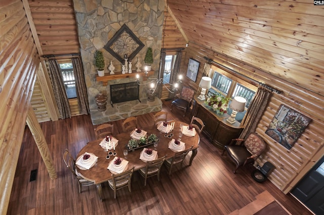 living room featuring log walls, wood finished floors, a high ceiling, and a stone fireplace