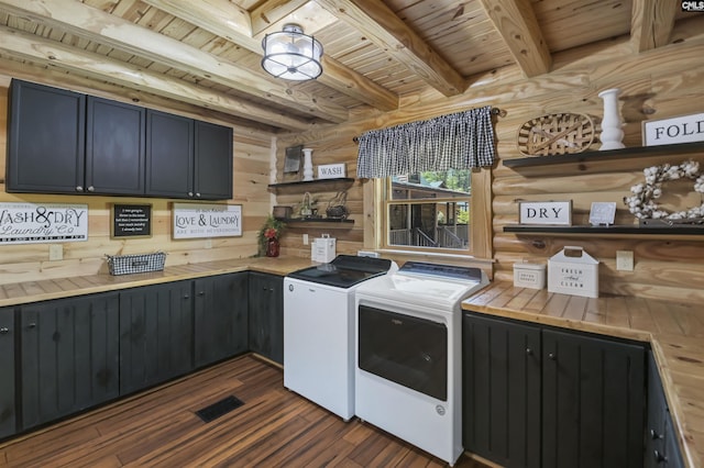 clothes washing area featuring cabinet space, dark wood finished floors, wood ceiling, and washer and clothes dryer