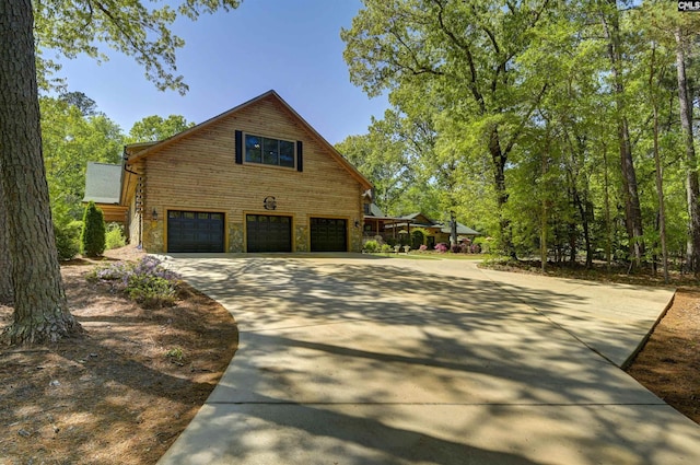 view of side of property featuring concrete driveway, log siding, and a garage