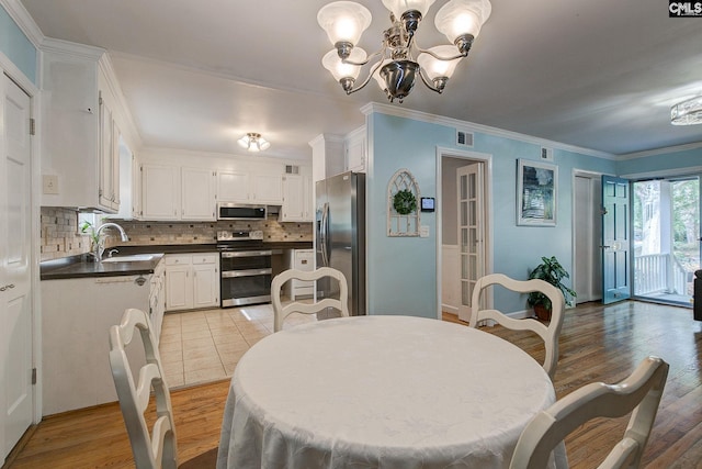dining space with light wood finished floors, visible vents, an inviting chandelier, and crown molding