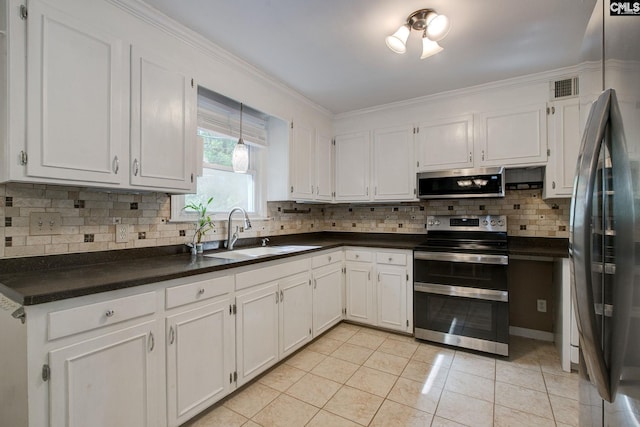kitchen with dark countertops, a sink, light tile patterned floors, stainless steel appliances, and backsplash