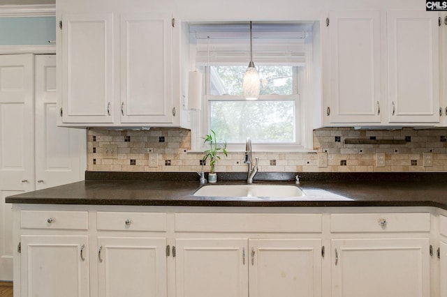 kitchen with white cabinets, dark countertops, and a sink