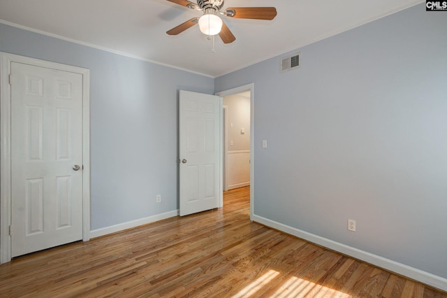 unfurnished bedroom featuring visible vents, crown molding, baseboards, light wood-style flooring, and ceiling fan