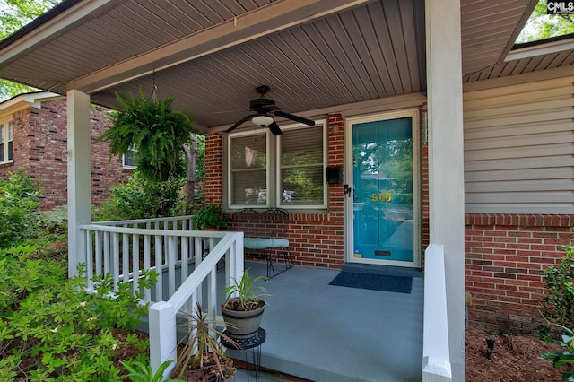 entrance to property with brick siding, a porch, and ceiling fan