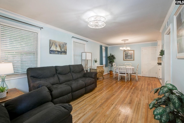 living area with a chandelier, light wood-style flooring, baseboards, and ornamental molding