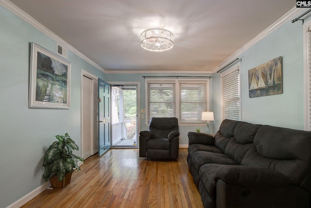 living room featuring an inviting chandelier, wood finished floors, visible vents, crown molding, and baseboards