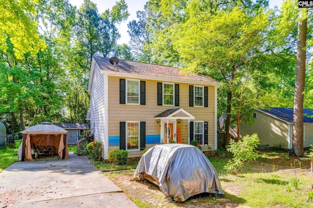 colonial house with a gazebo, driveway, and fence