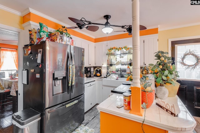 kitchen featuring stainless steel refrigerator with ice dispenser, dishwasher, white cabinetry, plenty of natural light, and ornamental molding