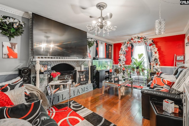 living area featuring a chandelier, ornamental molding, wood finished floors, and a fireplace