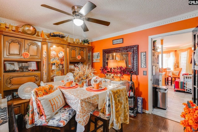 dining area featuring a ceiling fan, a textured ceiling, crown molding, and wood finished floors