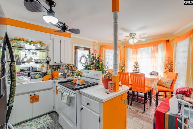 kitchen with white electric range oven, a ceiling fan, a peninsula, crown molding, and tile countertops