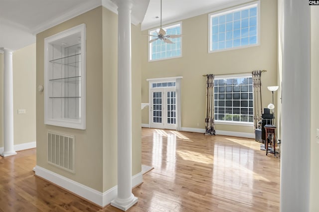 foyer entrance with wood finished floors, visible vents, crown molding, and decorative columns