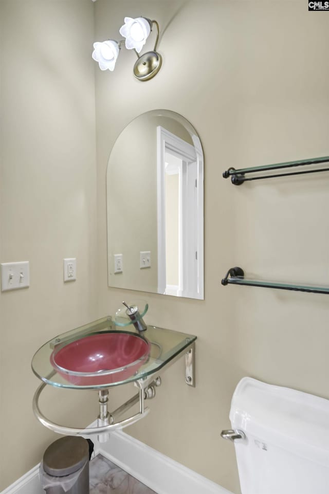 bathroom featuring baseboards, a sink, and marble finish floor