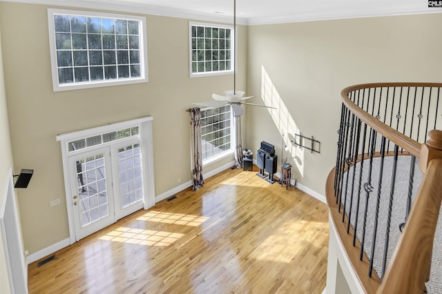 foyer entrance featuring baseboards, wood finished floors, and a towering ceiling