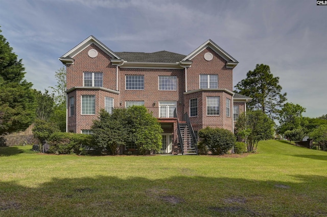 rear view of property with a lawn, brick siding, and stairs