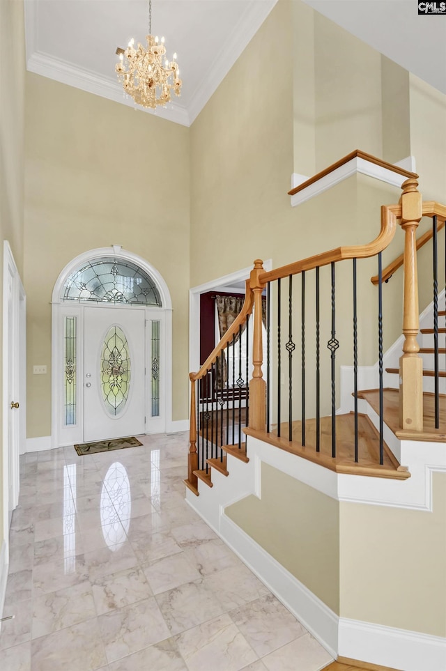 foyer entrance with a towering ceiling, a notable chandelier, marble finish floor, stairway, and crown molding