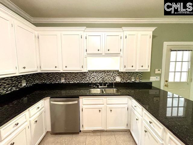 kitchen with stainless steel dishwasher, ornamental molding, a sink, tasteful backsplash, and white cabinetry