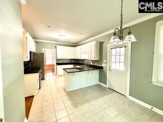 kitchen featuring tasteful backsplash, a chandelier, white cabinets, a peninsula, and ornamental molding