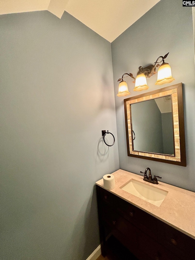 bathroom with baseboards, lofted ceiling, and vanity
