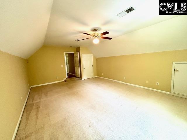 additional living space with vaulted ceiling, a ceiling fan, light carpet, baseboards, and visible vents