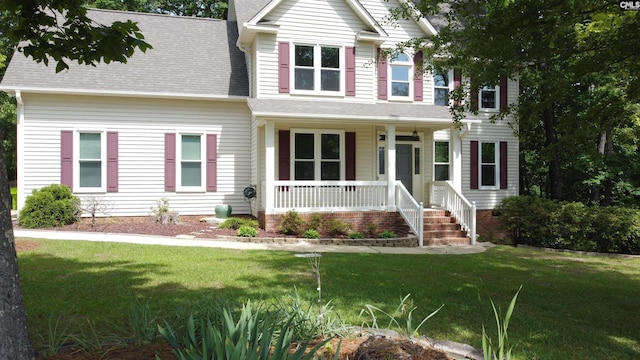 craftsman-style house featuring a porch, a shingled roof, and a front yard