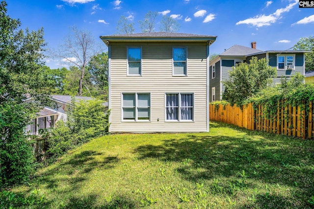rear view of property with fence and a yard