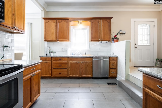 kitchen featuring light stone counters, brown cabinetry, stainless steel appliances, and a sink