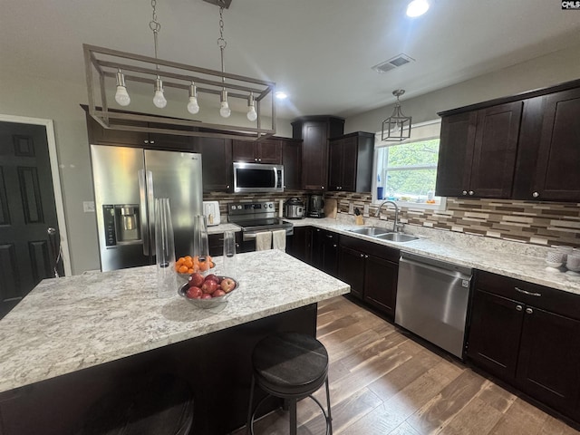 kitchen with a sink, tasteful backsplash, dark wood finished floors, visible vents, and appliances with stainless steel finishes