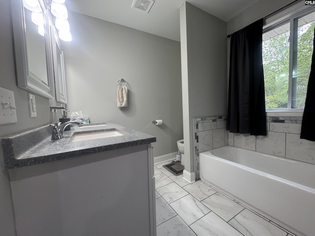 full bath with a sink, toilet, visible vents, marble finish floor, and a garden tub