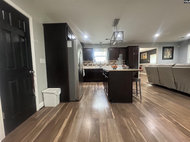 kitchen featuring open floor plan, light countertops, stainless steel fridge, and dark wood-type flooring