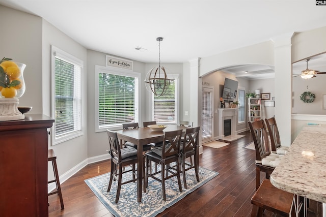 dining room featuring a fireplace with flush hearth, baseboards, dark wood-style flooring, and plenty of natural light