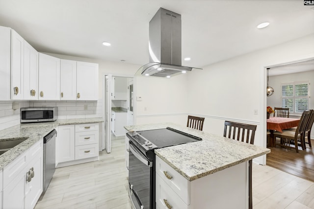 kitchen featuring white cabinets, stainless steel appliances, backsplash, island range hood, and a kitchen island