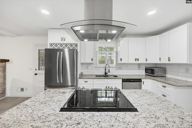 kitchen with white cabinets, stainless steel appliances, wood finished floors, a sink, and tasteful backsplash