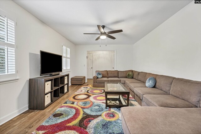 living area featuring light wood-style floors, baseboards, and ceiling fan