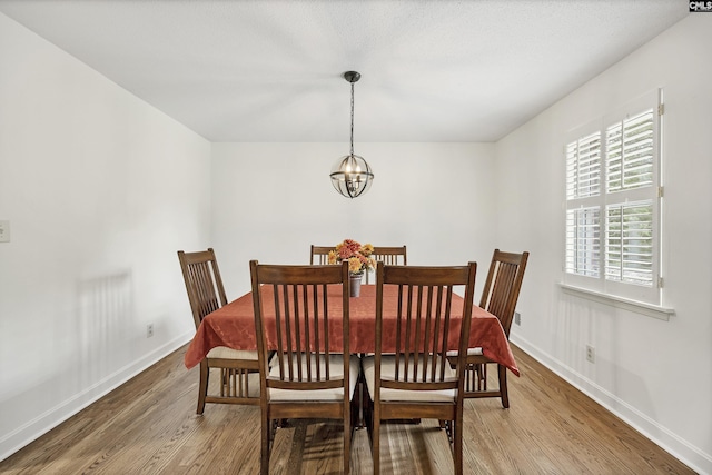dining room with baseboards, wood finished floors, and a chandelier